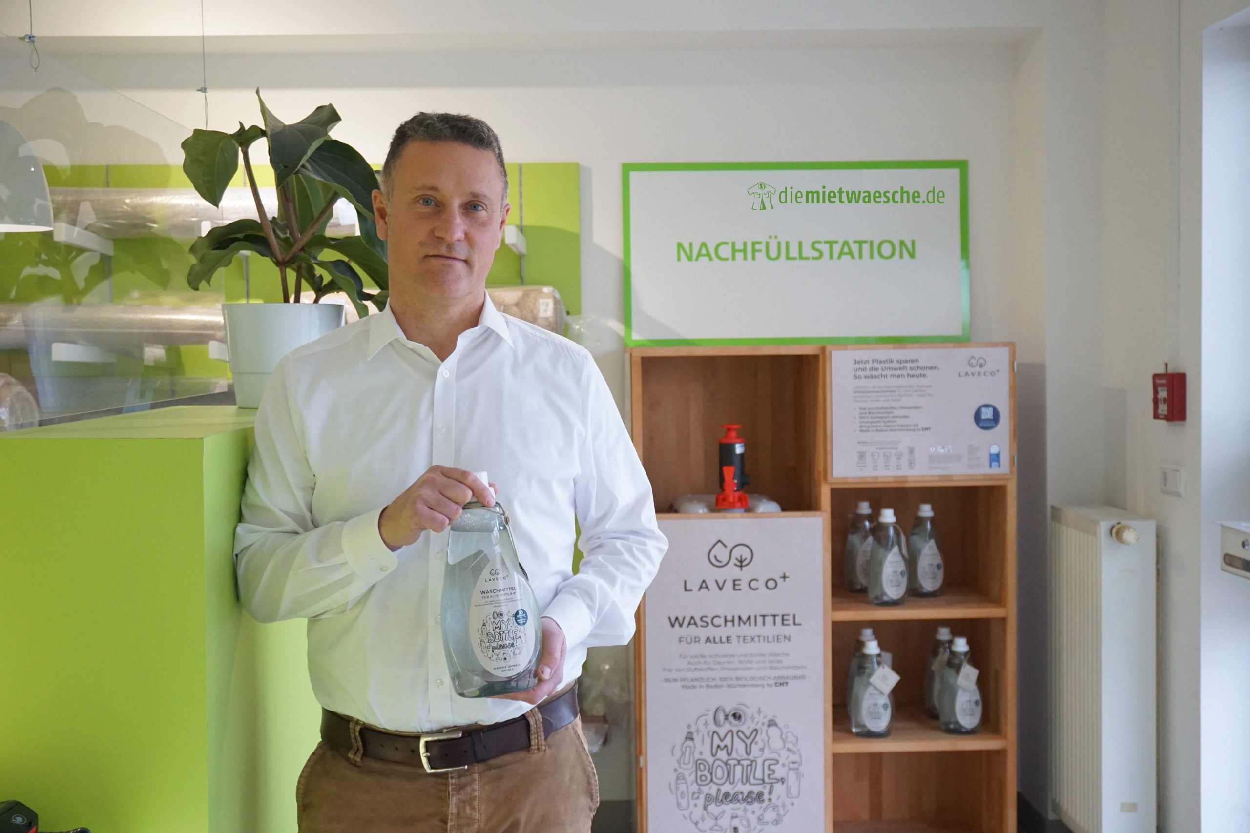 Henrik Rüss hält pflanzliches Waschmittel zum nachhaltigen Abfüllen von diemietwaesche.de