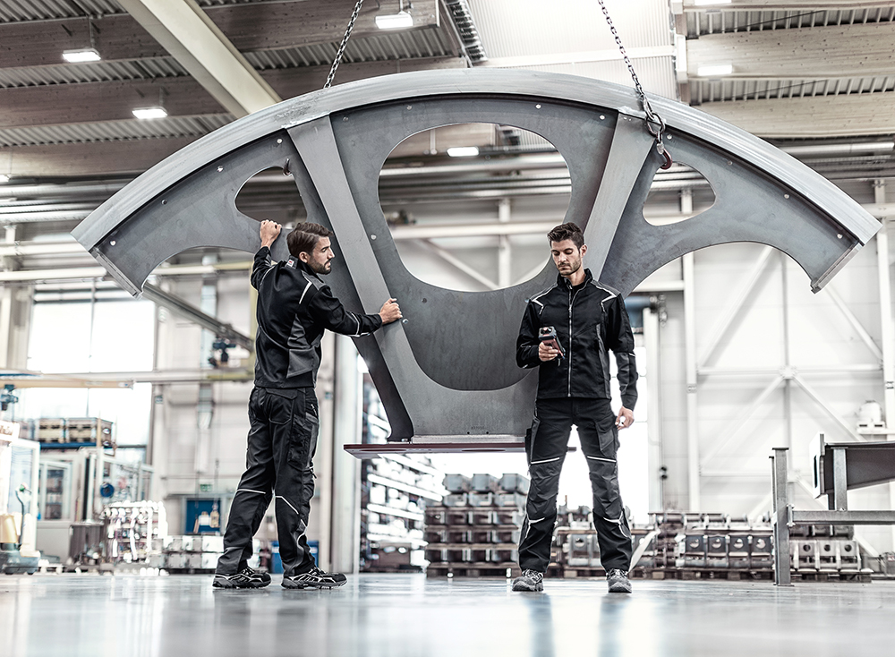 Zwei Männer in Fabrikhalle tragen Matterhorn Stretch Arbeitskleidung von diemietwaesche.de