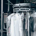 Arbeitskleidung, in Folie eingepackt, die an einer Wäschetransportstange einer Reinigungsfirma hängen