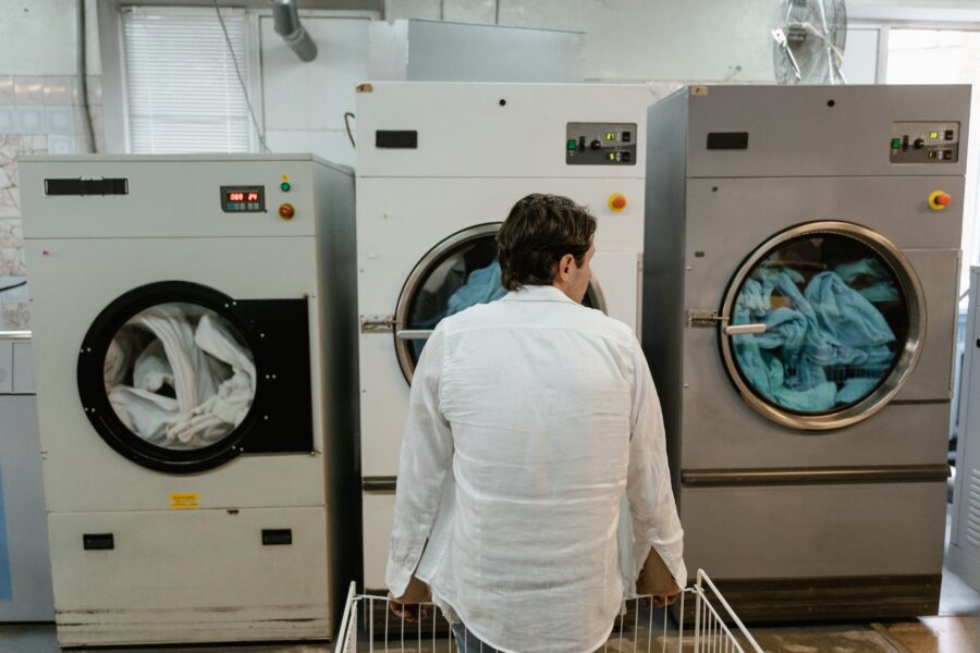 Mann in Weiß beobachtet Wäsche in großen Industriewaschmaschinen.