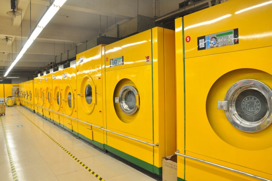 Reihe von großen gewerblichen gelben Waschmaschinen in einer industriellen Wäscherei.