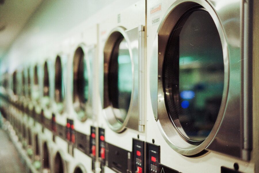 Reihe von gewerblichen Waschmaschinen mit Bullaugen in einem Waschsalon.